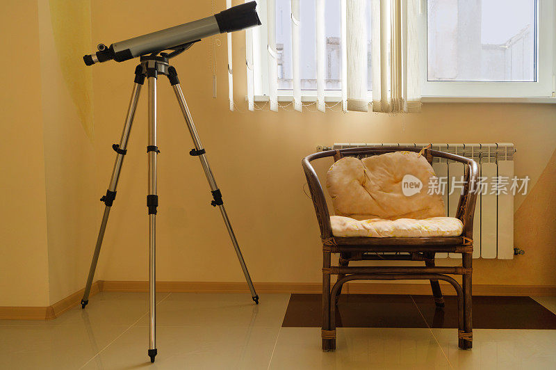 米色房间里，带靠垫的藤椅旁的家用小望远镜
