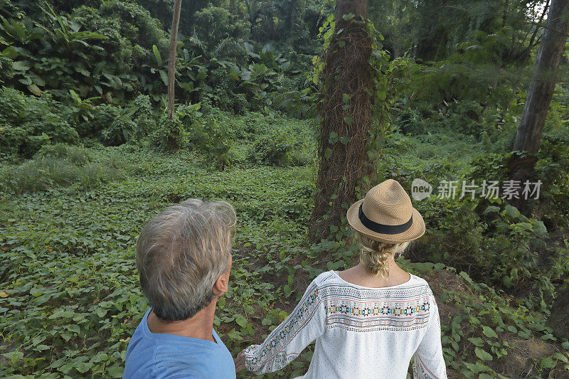 一对夫妇凝视着丛林，一个女人向前走去