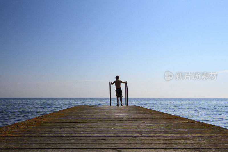 一个孤独的男孩在码头上洗夏天的澡