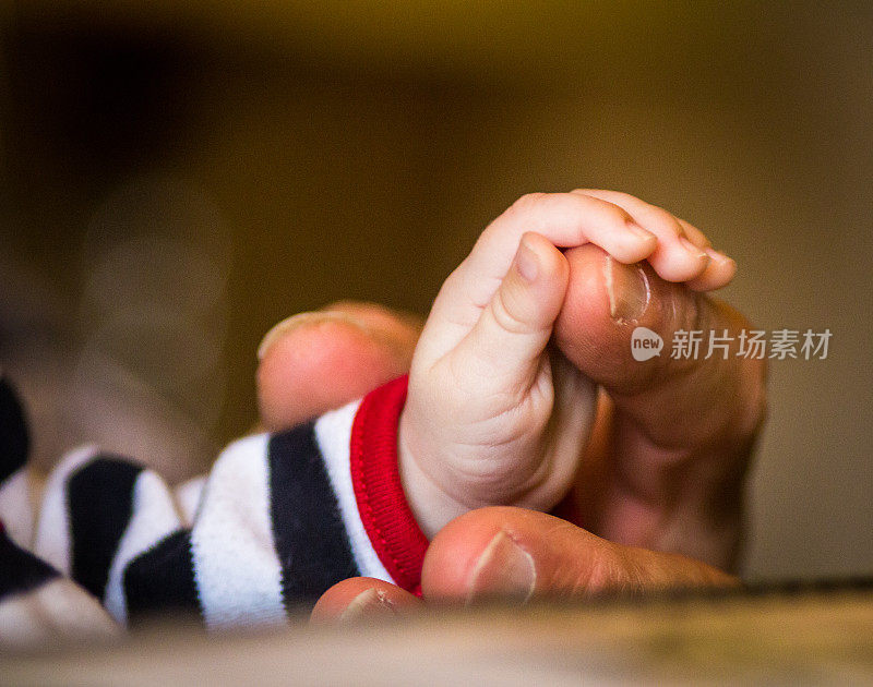 一个大男人的手牵着一个小婴儿的手的微距特写