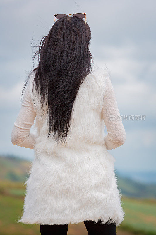 女人站在山顶上，看着自然宁静的景色，放松