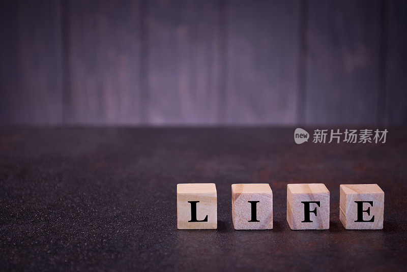 “生活”字在木方上，在深色的背景上，木方上有浅色的符号、符号