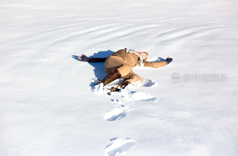 女人躺在阳光明媚的新雪