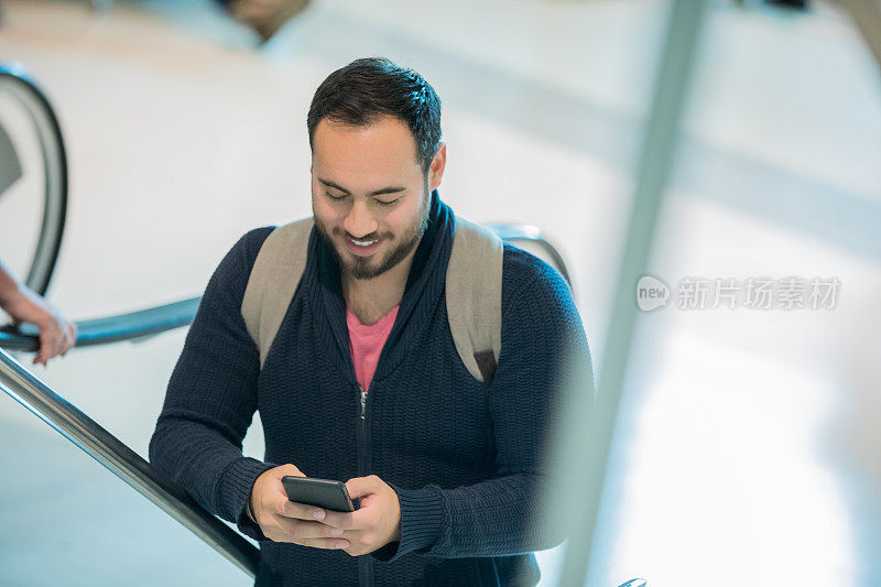 中年男性在机场自动扶梯上查看手机