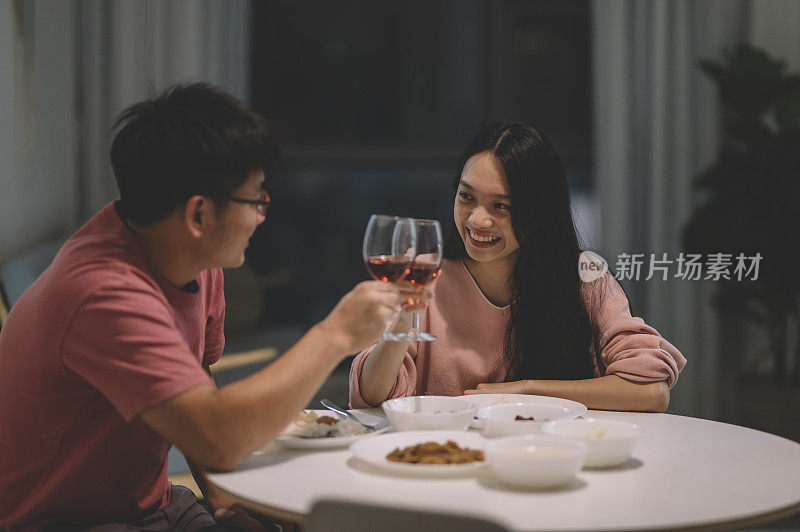 一对亚洲华人夫妇周末在家吃晚餐，喝红酒，吃中餐