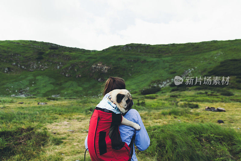 女人和狗在背包里登山