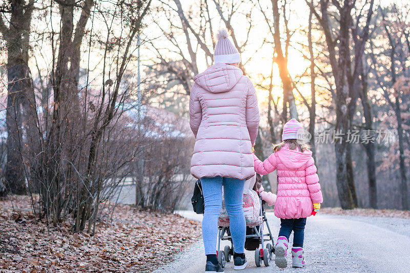 年轻的妈妈和她的孩子们在公园里散步。