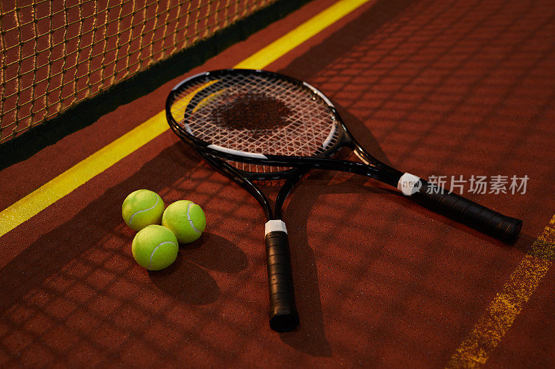 参赛者的网球拍和树网球躺在网球场的阴影，娱乐游戏的概念