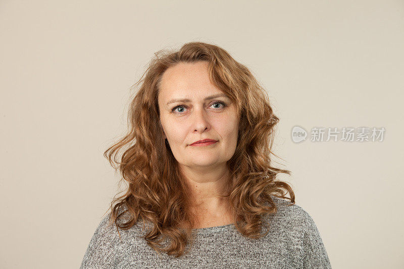 一个50岁的长卷发女人的工作室肖像
