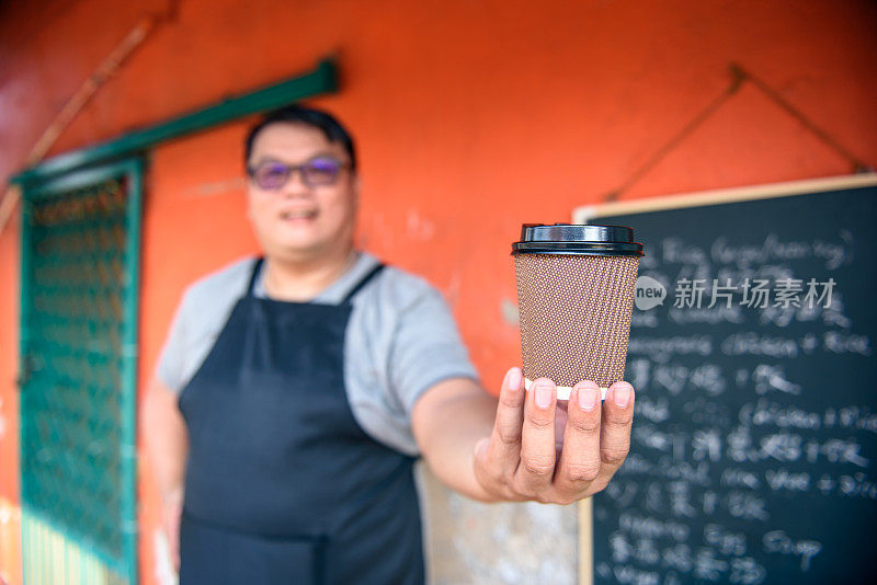 亚洲咖啡师的肖像与纸咖啡杯