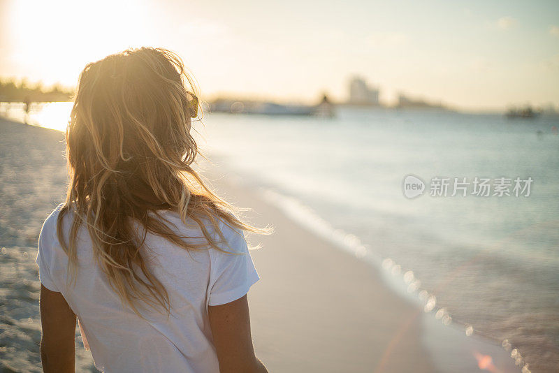 女人放松在海滩上日落