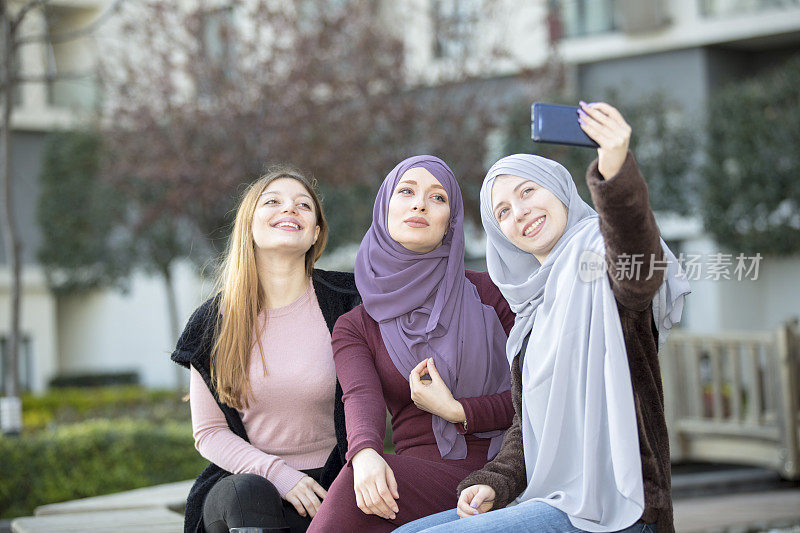 三个漂亮的穆斯林女孩玩智能手机