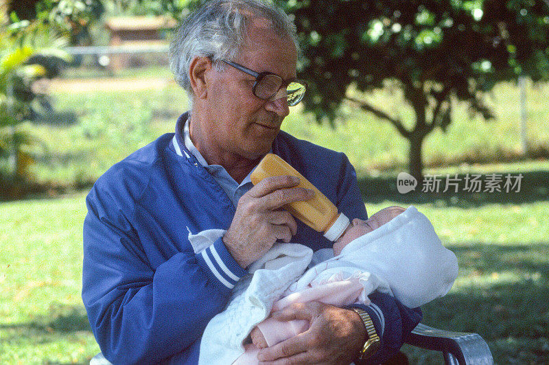 爷爷在户外给刚出生的小孙女一瓶奶瓶