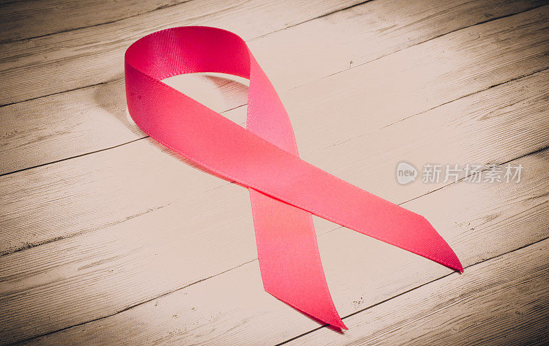 木制背景上的粉色丝带是乳腺癌的象征，是与癌症抗争的标志