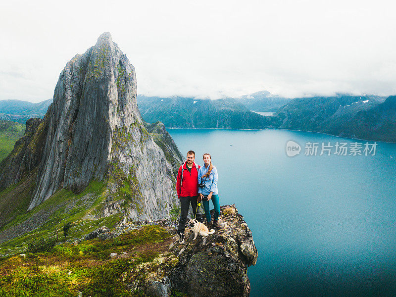 一对夫妇和狗高兴地在山顶上与峡湾的看法