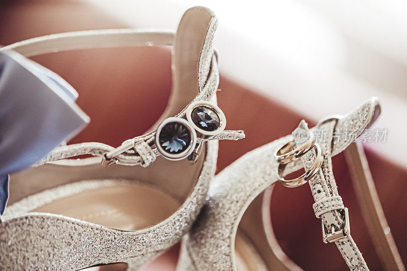 一双新娘的凉鞋，上面挂着一副结婚戒指