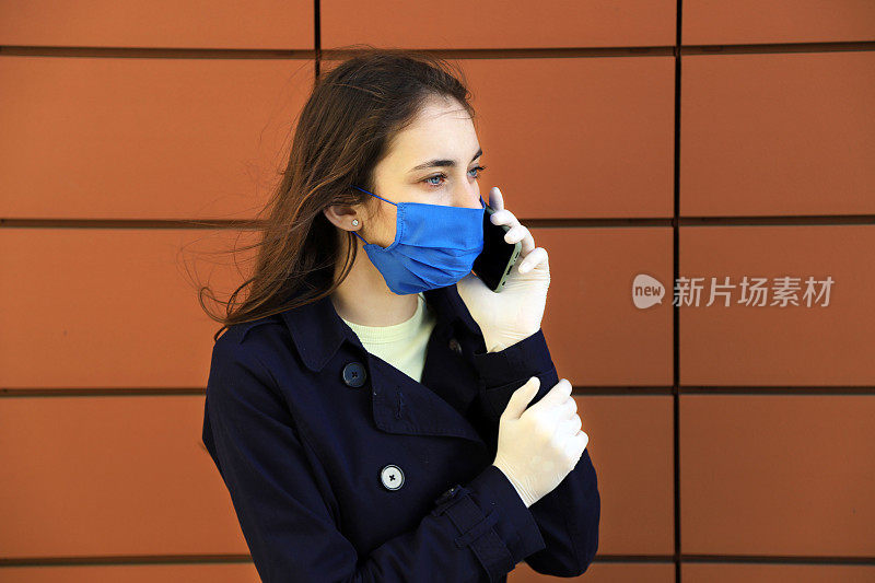 一位戴着面罩和手套的年轻女子正在讲电话