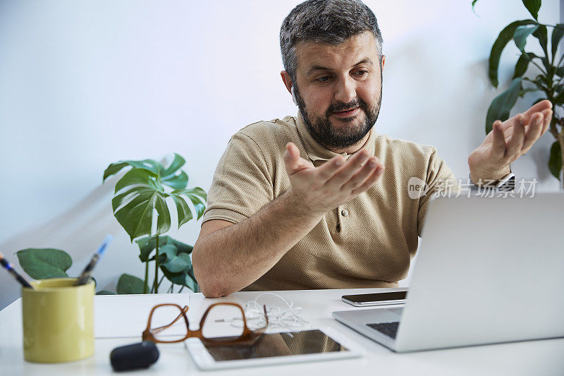 一个年轻人在他的家庭办公室里对着电脑说话