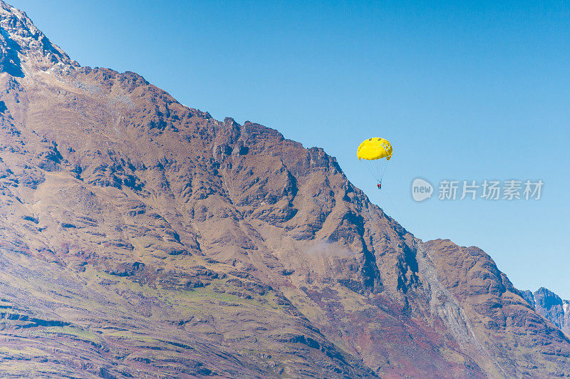 旅游活动滑翔伞飞越皇后镇和新西兰瓦卡蒂普湖山脉。