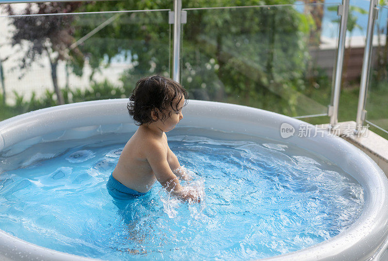 可爱的小男孩在自家阳台上的充气游泳池里玩耍