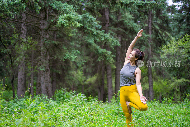 年轻的亚洲女人在森林里练习瑜伽