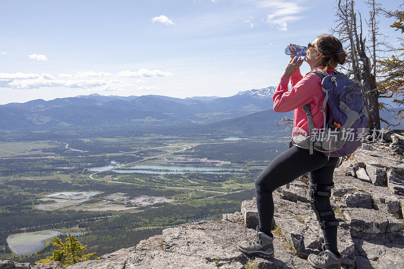 女性徒步旅行者在山脊上休息时补充水分