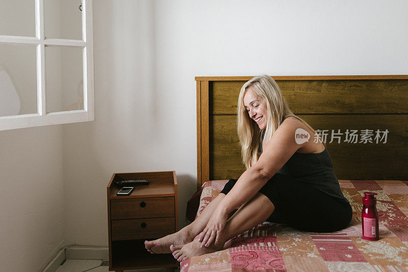 女人坐在床上往腿上涂药膏
