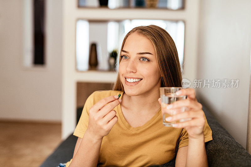 年轻健康的金发女子正在服用补品