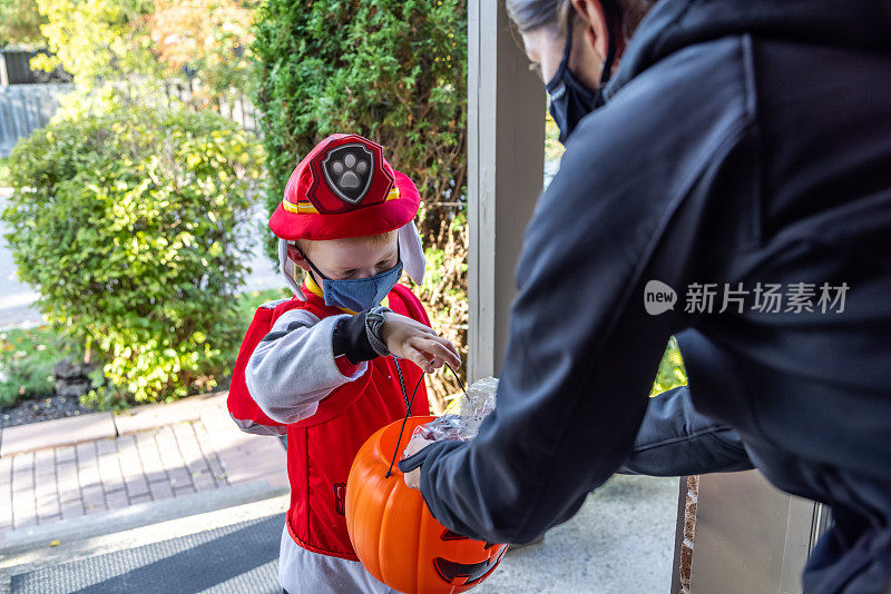小男孩戴着防护面具在万圣节接受糖果