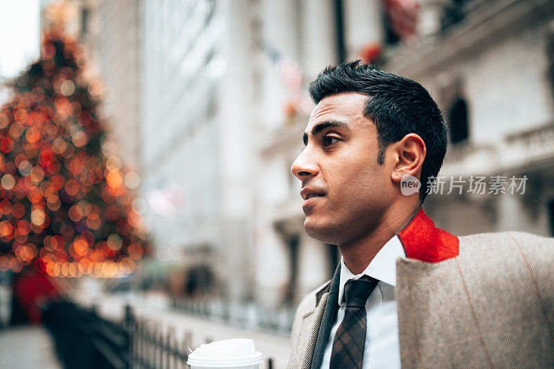 一名印度商人正在华尔街看圣诞报纸