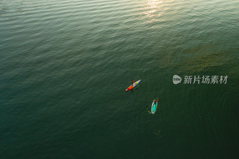 从空中俯瞰日落时分湖面上的两个划桨者