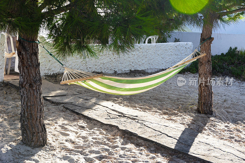在葡萄牙阿尔加维海岸的一所房子的入口处，悬挂在两棵松树之间的布床