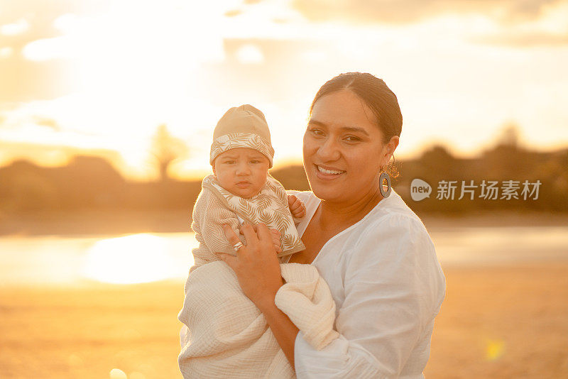 夕阳西下，微笑的妈妈和她可爱的宝宝。