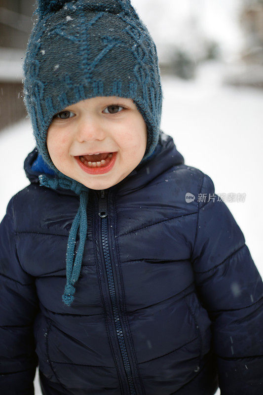 一个可爱的蹒跚学步的孩子享受第一次吹雪的肖像