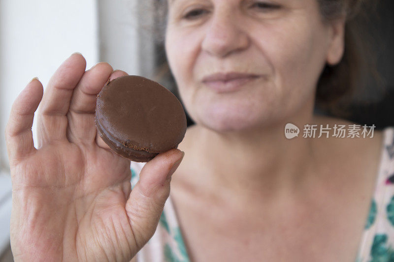 微笑快乐的老年妇女拿着巧克力饼干