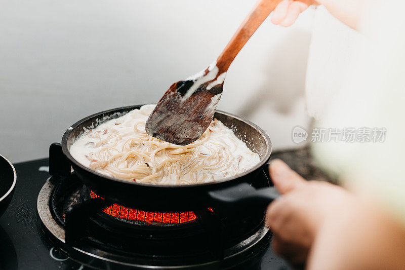 烤意面是在厨房背景的煎锅里煮的