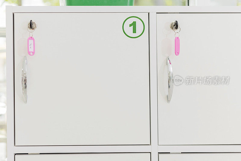 白色的小储物柜，钥匙插在编号为1的锁上