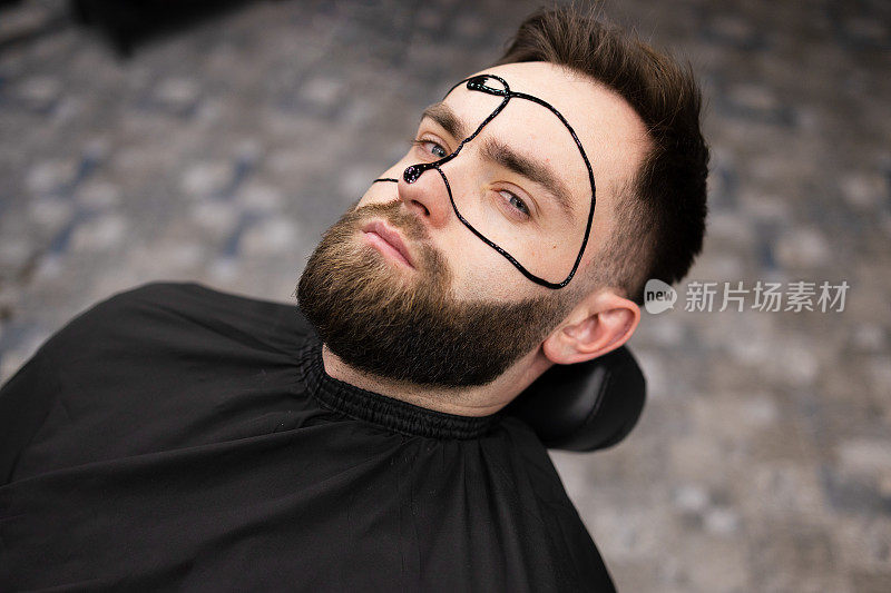 男士化妆面膜用黑色面膜滋润脸部，护理肌肤。