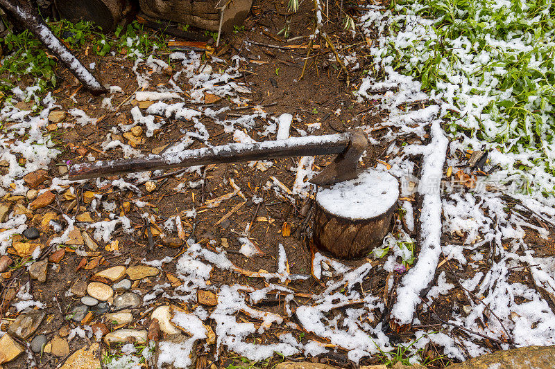 一把斧头插进了雪地里的一块木头里