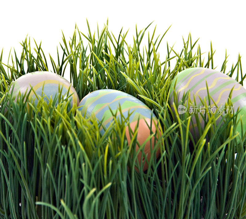 手工装饰的复活节彩蛋隐藏在草-孤立的白色