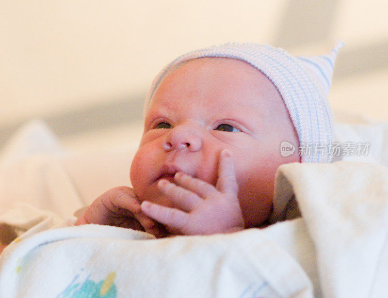 新生婴儿睁开眼睛，一只手放在脸上