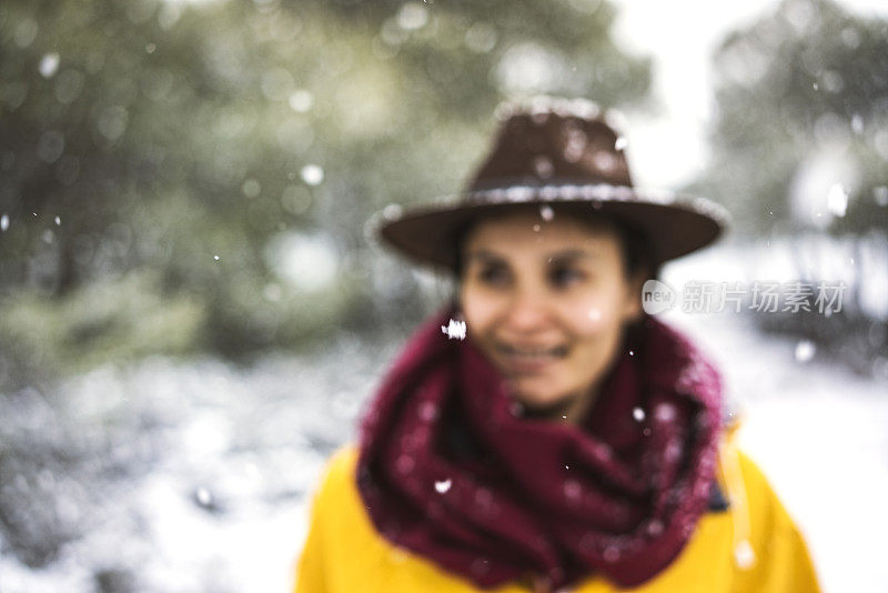 穿着黄色雨衣的女旅行者正在享受下雪天