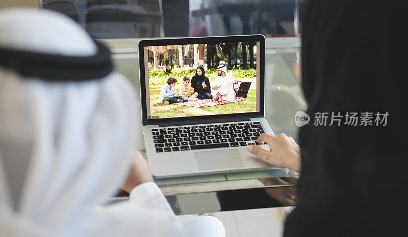 中东夫妇在笔记本电脑上查看家庭野餐照片