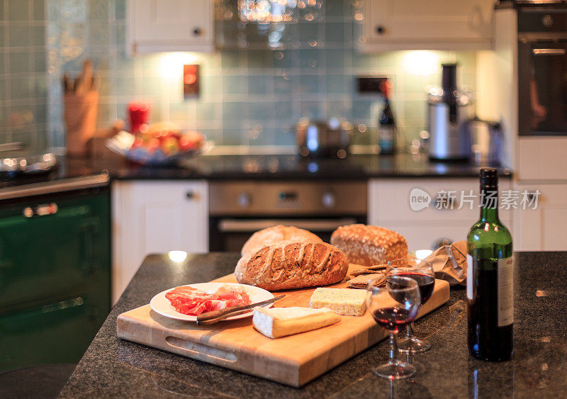 面包板与火腿，奶酪，葡萄酒和面包厨房背景
