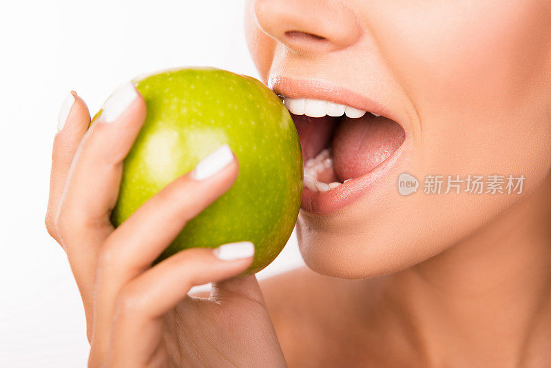 一个美丽健康的女孩咬苹果的特写照片