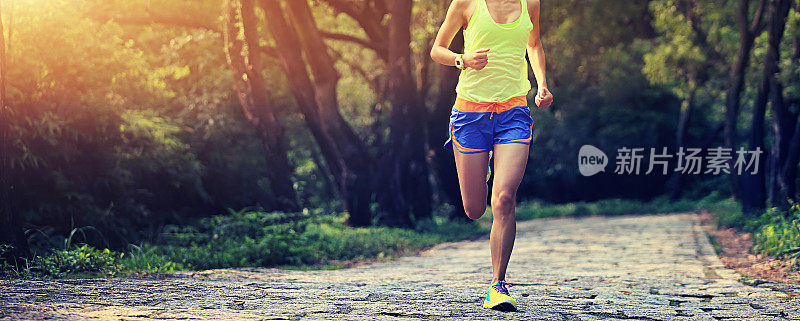 一个年轻的健身女性在森林小径上跑步