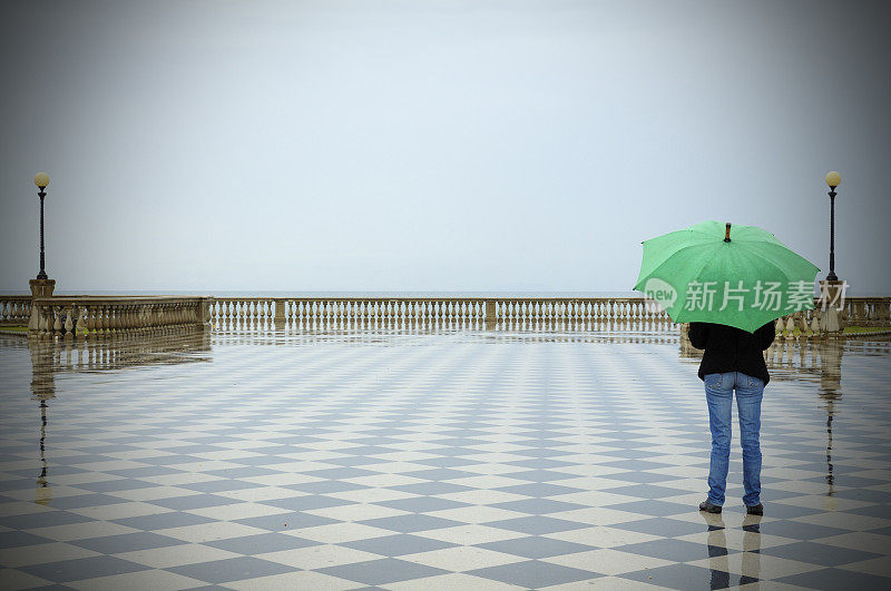 在方格城镇广场上拿着雨伞的女人