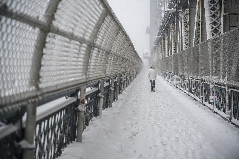 少女走在雪下的曼哈顿人行桥