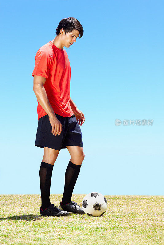 一个年轻人在球场上踢足球