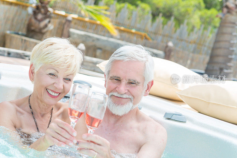 老夫妇在热水浴缸里喝葡萄酒